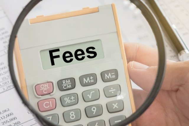 電卓の画面に『Fees』と表示され、虫眼鏡で拡大された様子。ビジネスにおける手数料やコスト管理を象徴するイメージ。