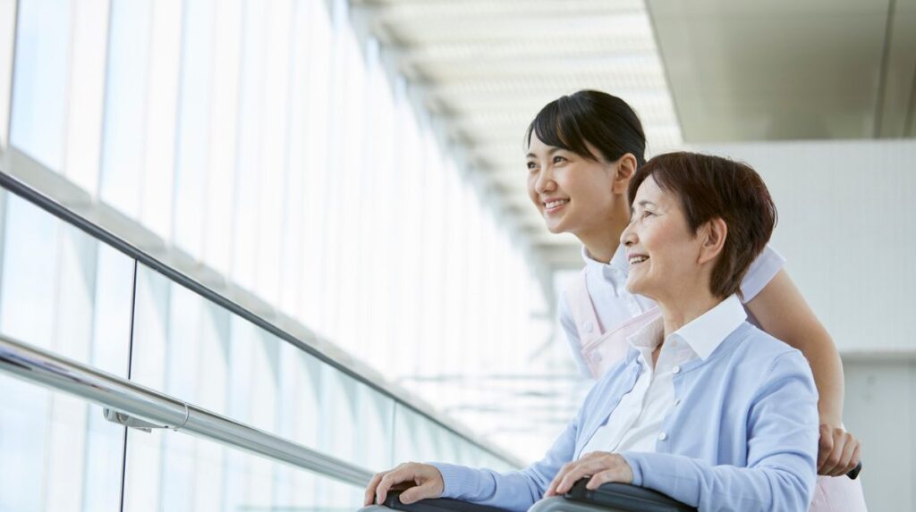 車いすの高齢者と会話をしている介護士