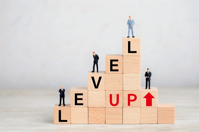 LEVEL UPと書かれた木のブロックの上にミニチュアの人型が乗っている画像