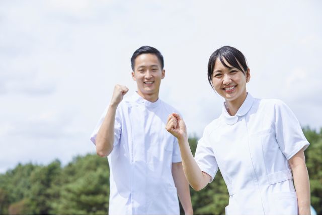 笑顔でガッツポーズをしている男女の外国人介護士