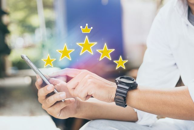 スマホでオンライン学習サイトのレビューを比較している外国人