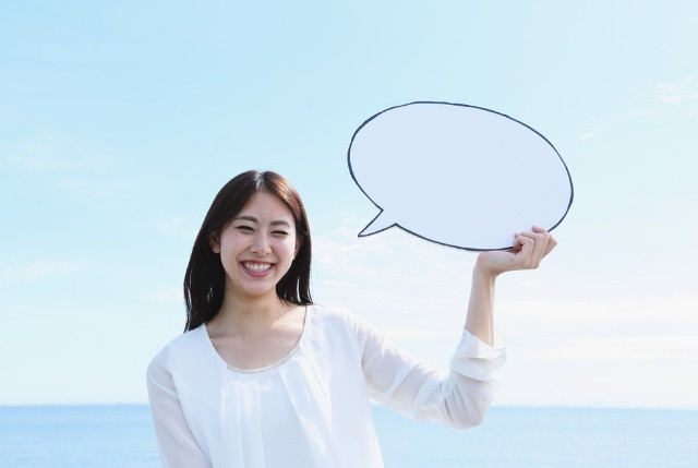 海を背景に吹き出しを手にしている笑顔の女性