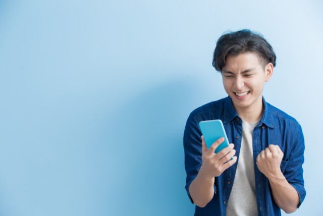 アプリを使って漢字学習を行っているデニムのシャツを着た外国人男性