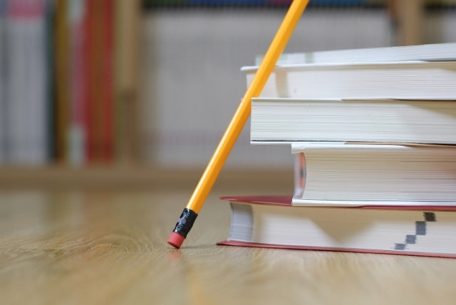 積み重ねた試験の参考書と鉛筆