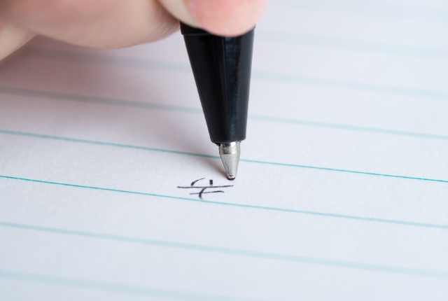 ノートに「幸」という漢字を書くペン先のクローズアップ。漢字学習や外国人スタッフの筆記練習をイメージした写真。