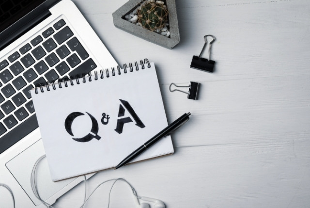 ノートに「Q&A」と書かれたページがノートパソコンの上に置かれている。日本語eラーニング導入に関する質問と回答を象徴するイメージ。
