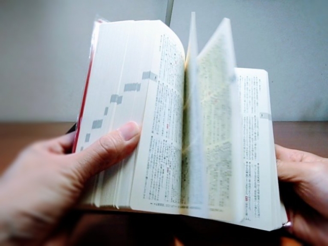 辞書をめくる手元の写真。外国人社員向けの漢字学習や教材紹介の記事イメージに最適な画像。