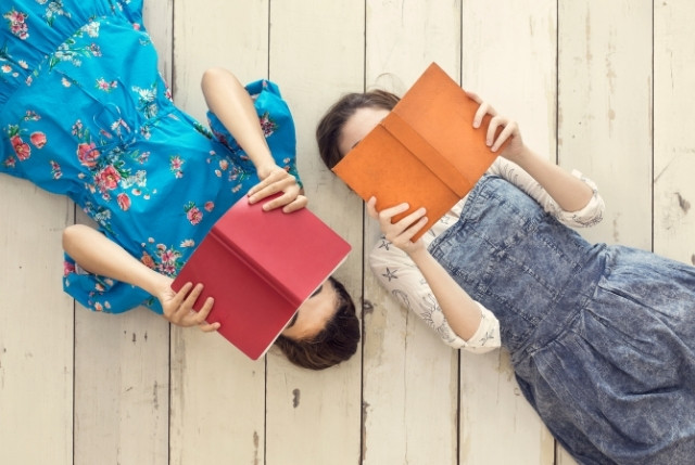 床に寝転んで本を読む2人の女性。学習や読書、日本語教育の楽しさをイメージさせる写真。