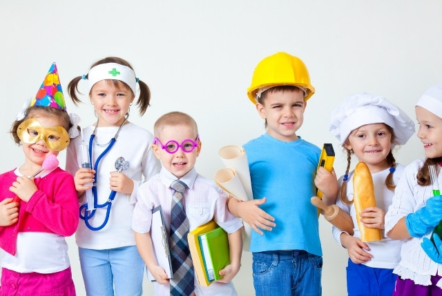 職業の衣装を着た子供たちが並ぶ様子。ロールプレイングで日本語を学ぶ幼児教育のイメージ。