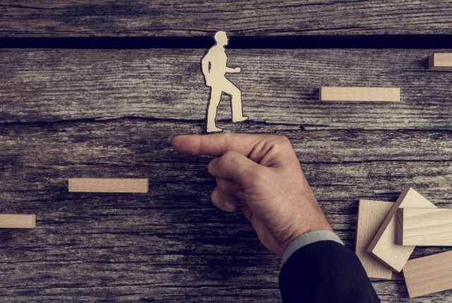 階段を上る人のシルエットを指で支える様子。企業ができる支援やキャリアアップを象徴するイメージ写真。