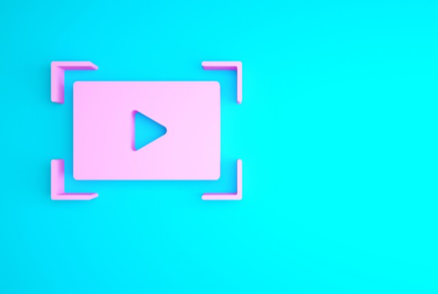 ピンクの再生アイコンが映る動画コンテンツを象徴するイラスト。特定技能試験のオンライン学習やリモート教育を解説する記事用。