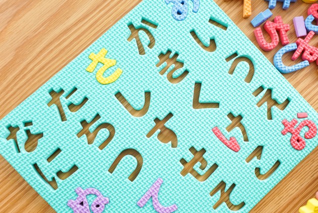 ひらがなのパズルマットとカラフルな文字ピース。日本語学習や文字教育をイメージさせる教材。