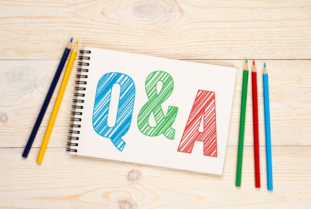 ノートに大きく「Q&A」と書かれ、周囲に色鉛筆が並ぶ画像。特定技能2号試験や学習に関するよくある質問の解説をイメージ。