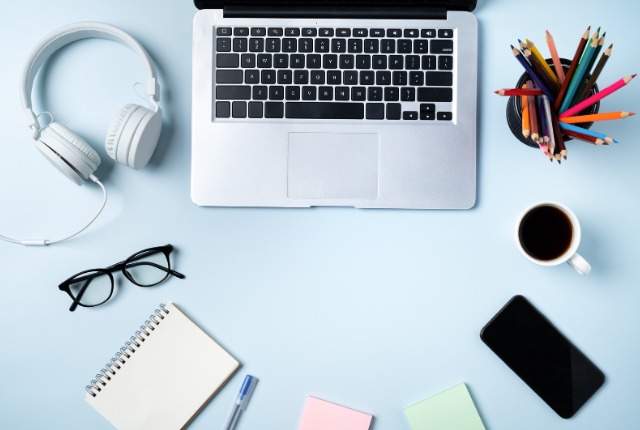 ノートパソコンとヘッドホン、ノートや文具が並ぶデスク。日本語学習やオンラインeラーニングの学習環境イメージ。