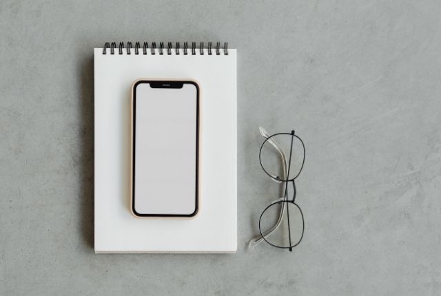 スマートフォンとノート、眼鏡を並べたデジタル学習やオンライン研修をイメージしたワークスペース