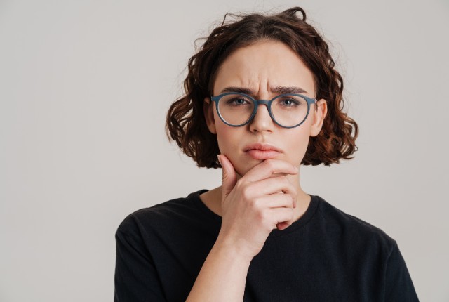 日本語表現や業務ルールの意味に戸惑い、考え込む外国人社員のイメージ写真