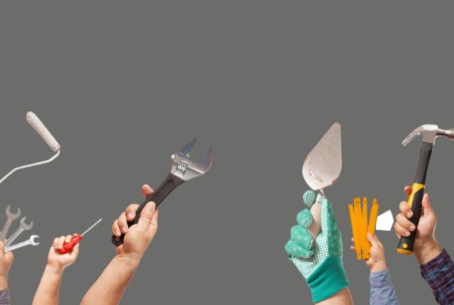 さまざまな工具を手に持つ作業者の腕が並ぶ、技能労働を象徴するイメージ写真