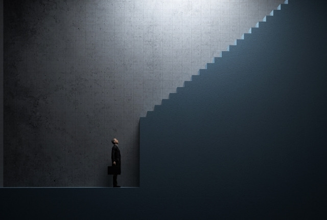 外国人受験の課題と壁 暗い空間の中で階段を見上げるスーツ姿の人物が立っているイメージ写真