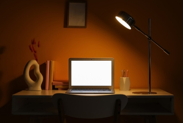 デスクライトに照らされた机の上にノートPCが置かれた自宅の学習スペース