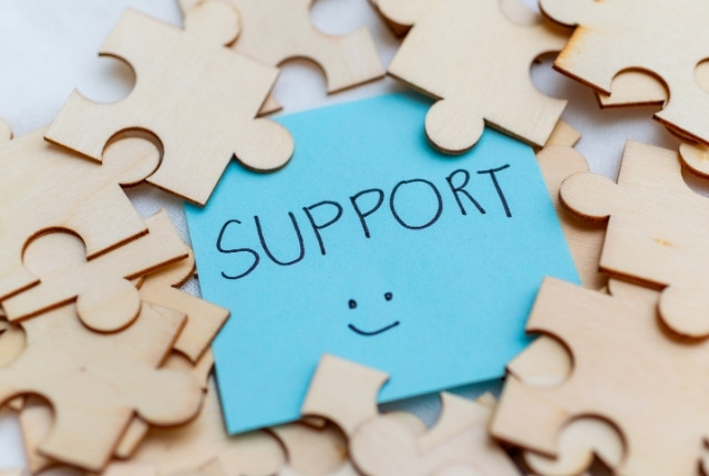 企業による学習支援策 木製のパズルピースに囲まれた青いメモに「SUPPORT」と書かれている写真