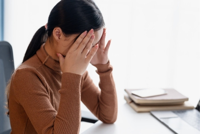 介護福祉士試験の不安と壁 机に向かい両手で顔を覆い悩んでいる女性の様子