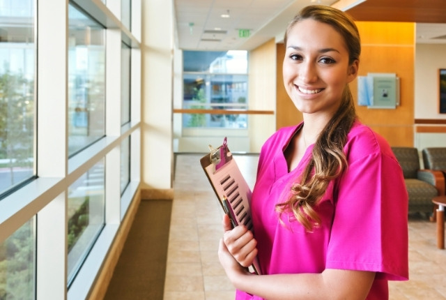 医療・介護施設の廊下で書類を持った女性スタッフが立っている様子