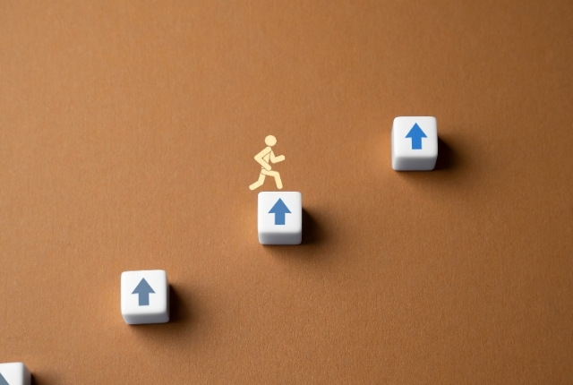 上向き矢印の段差を人型アイコンが進む、日本語レベルの上達を表すイメージ写真