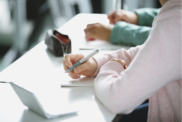 机に向かってノートに書き込みをしている学習者の手元の様子