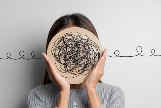 伝わらない原因を考える 顔の前に線が絡まったイラストを持つ女性のイメージ