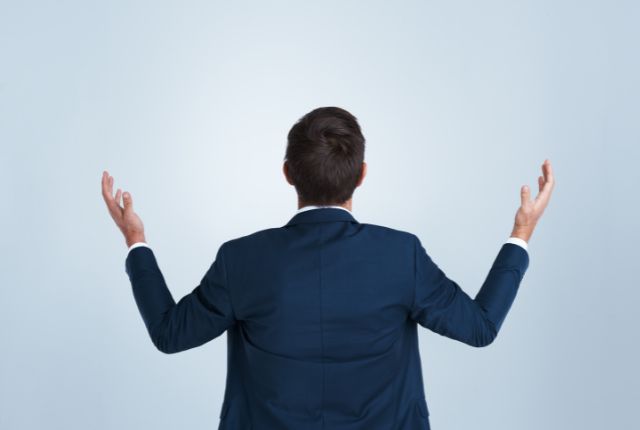 漢字が覚えられない理由 背中を向けて両手を広げ、困った様子を見せるスーツ姿の男性のイメージ写真